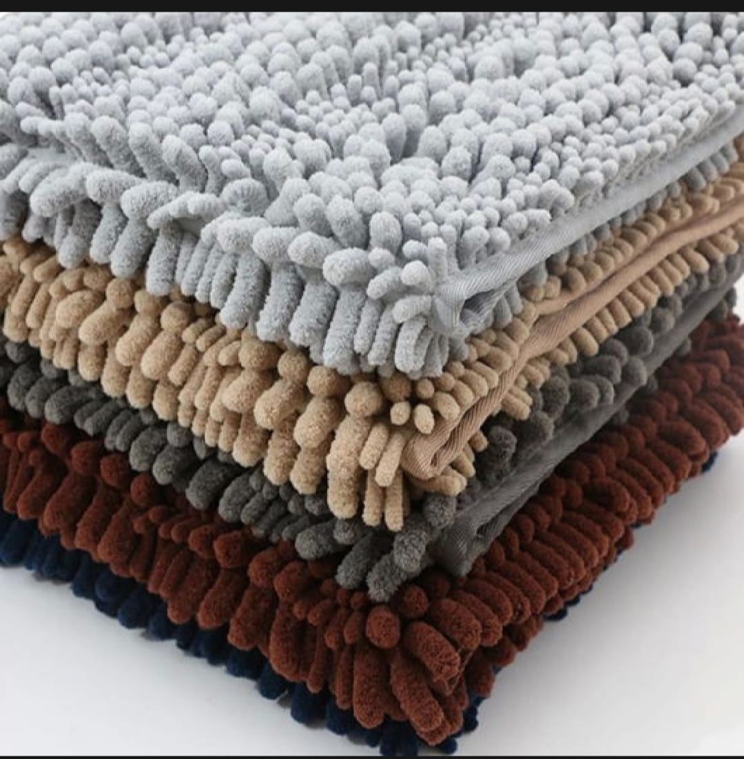 Stack of textured bath mats in various colors on a white background