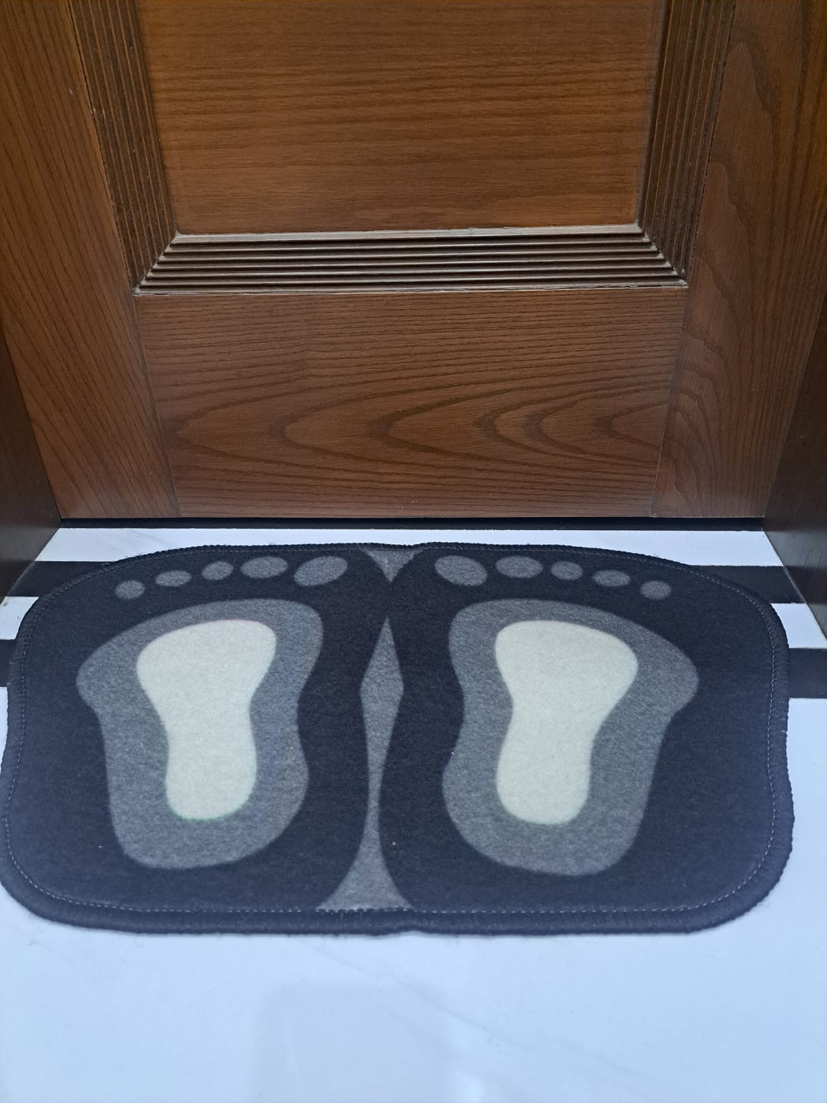 Doormat with footprints in front of a wooden door