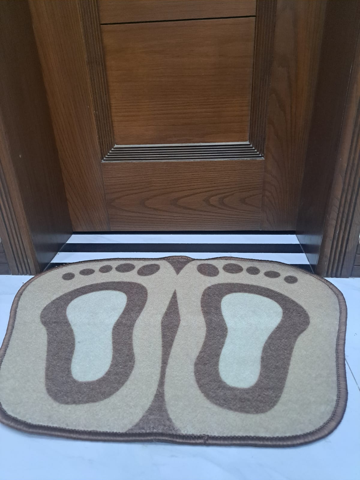 Doormat with footprints in front of a wooden door