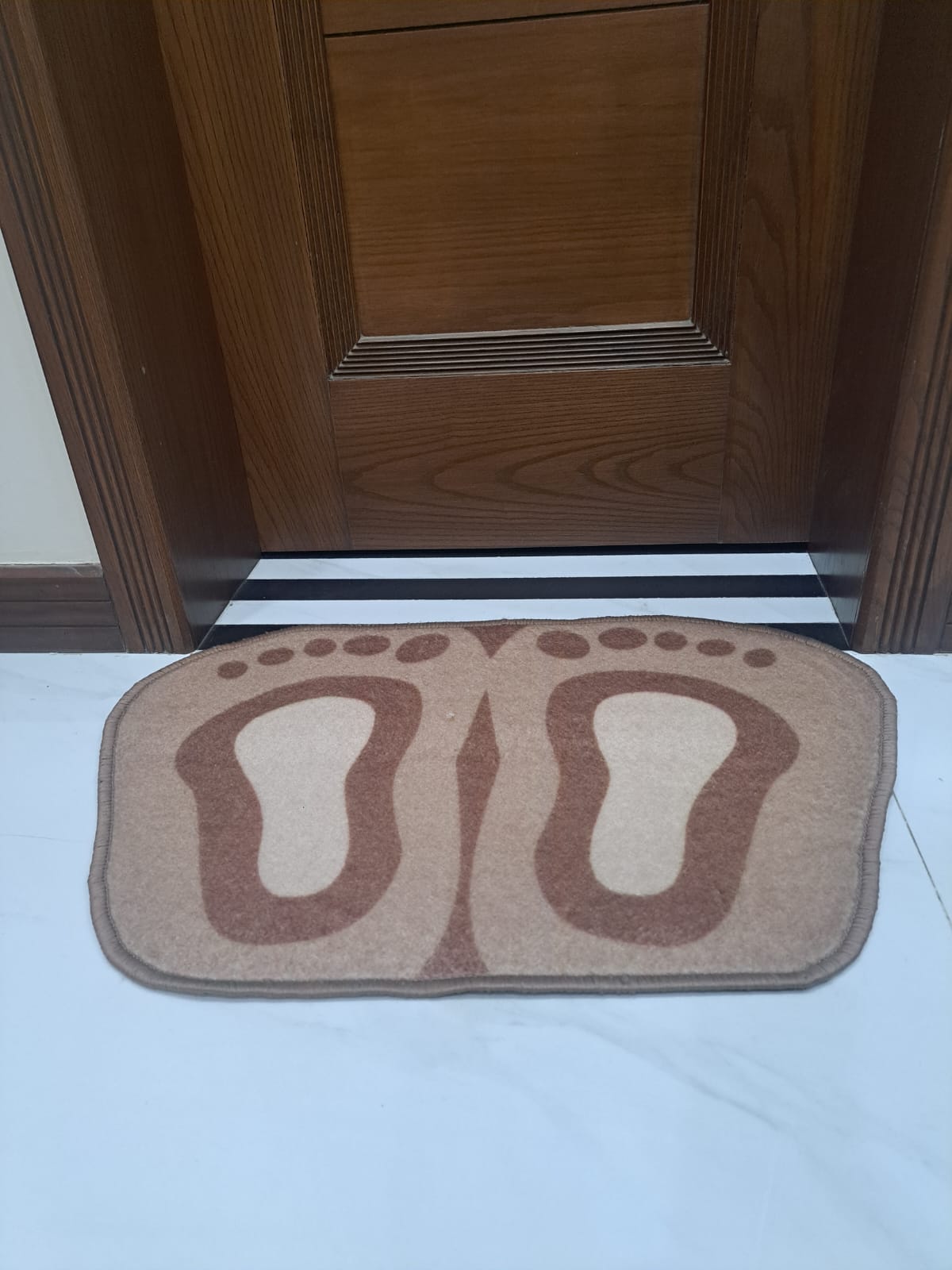 Doormat with footprints design in front of a wooden door
