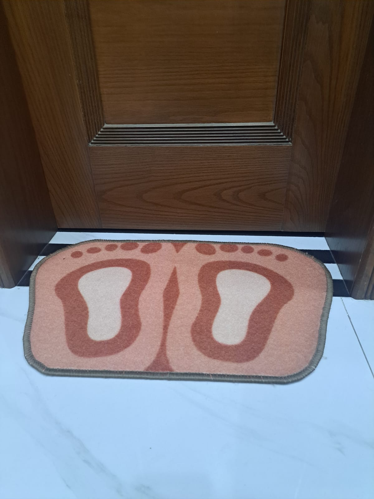 Doormat with footprints in front of a wooden door