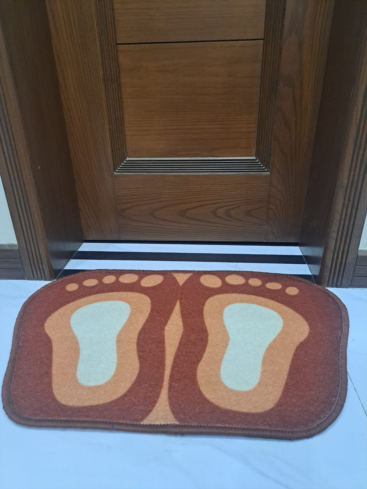 Doormat with footprints design in front of a wooden door