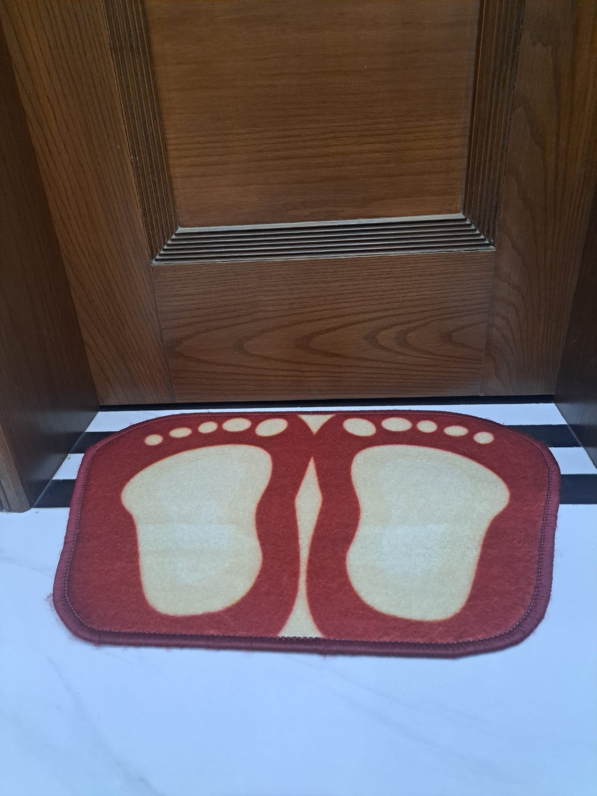 Doormat with footprints design in front of a wooden door