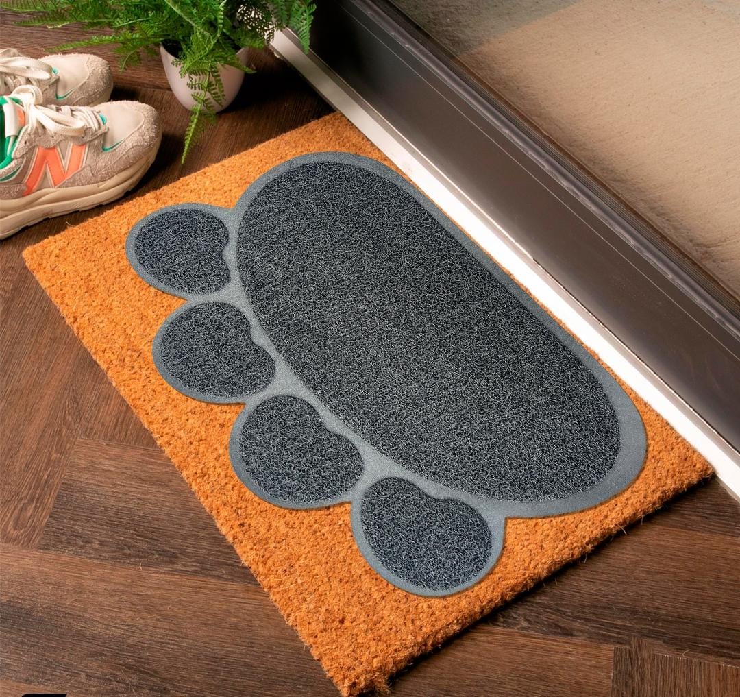 Doormat with a paw print design on a wooden floor next to a door.