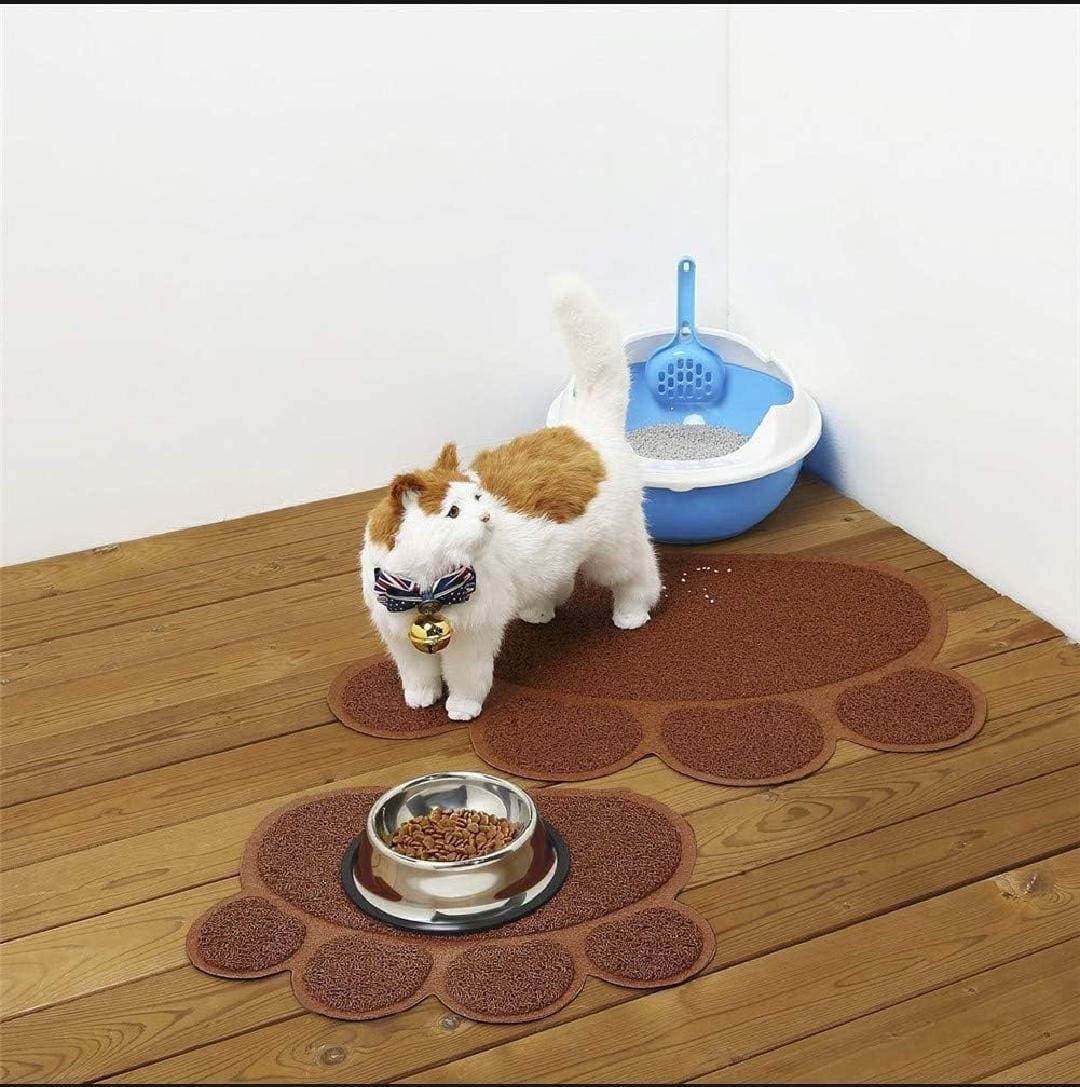 Two small dogs standing on a paw-shaped mat with a bowl of food in front of them, next to a blue litter box.