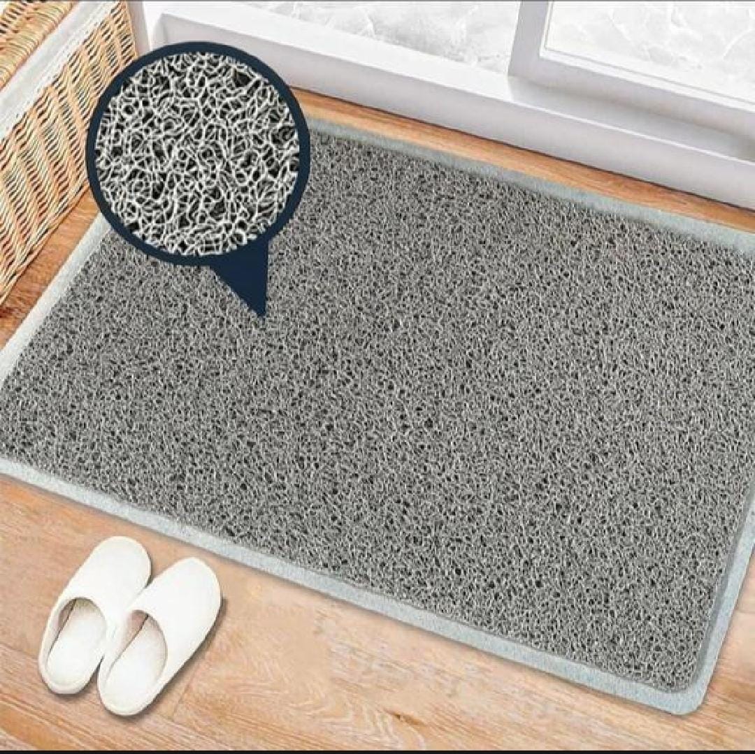 Gray doormat with textured surface on a wooden floor, showing close-up of texture.