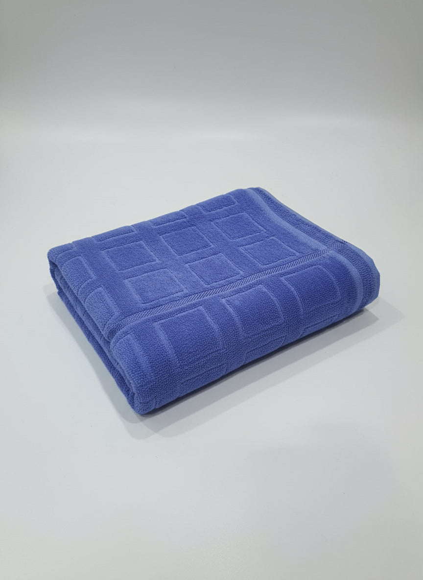 Folded blue towel on a cardboard box with a tiled floor background