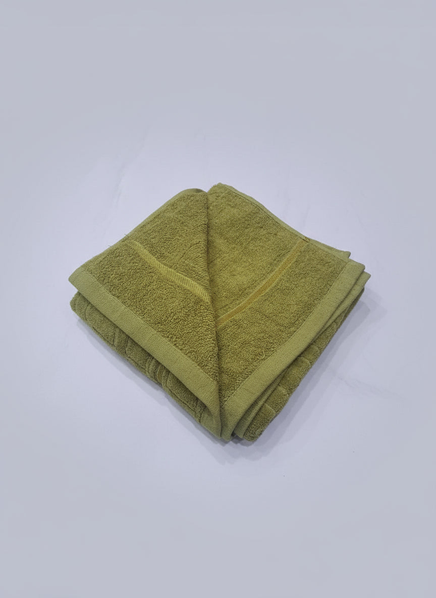 Green towel on a wooden surface with a white tiled floor background