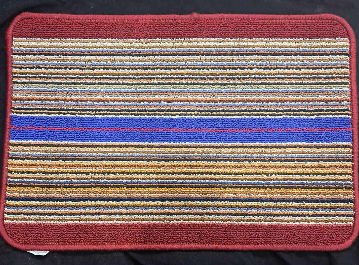 Multicolored striped rug with a red border on a black background