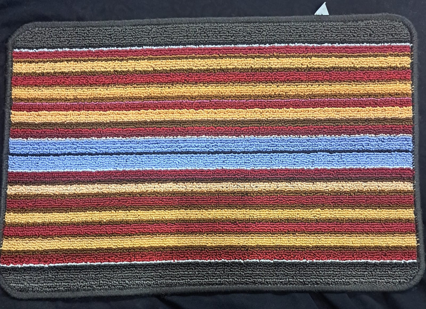 Striped bath mat with multicolor pattern on a dark background