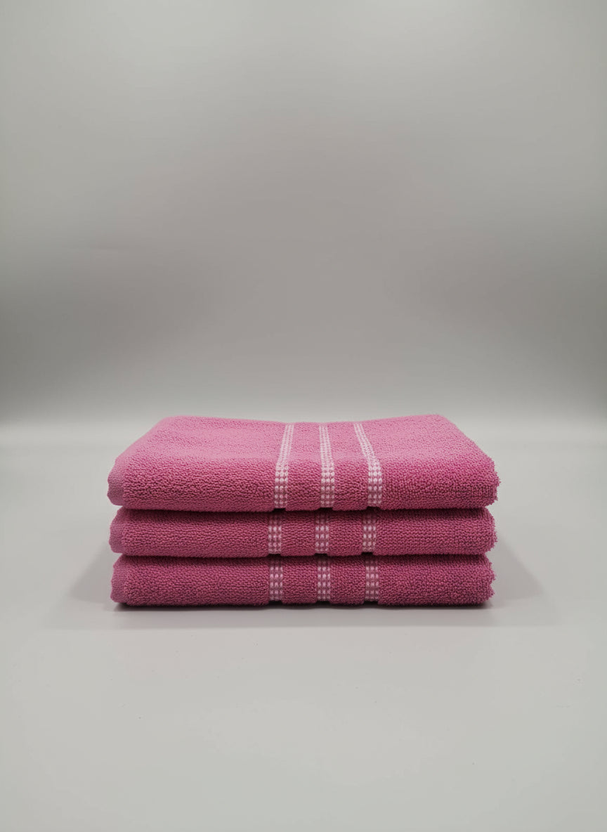 Stack of pink towels with white stripes on a tiled floor