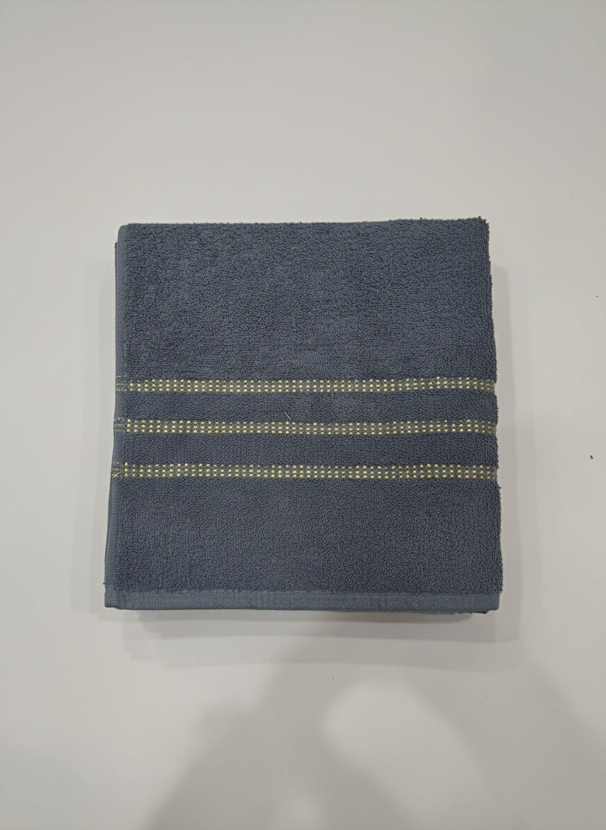 Blue towel with gold stripes on a cardboard box against a tiled floor background
