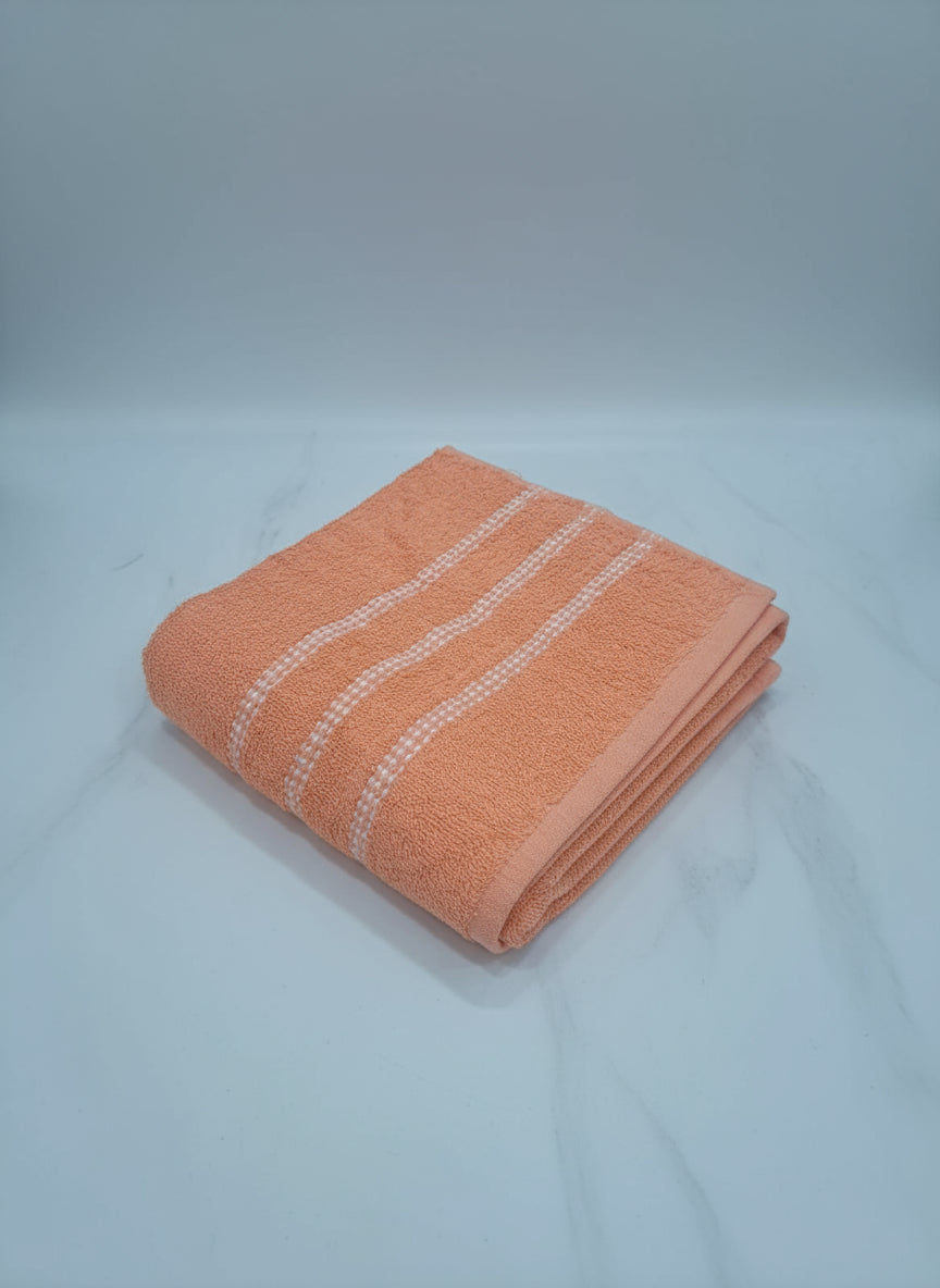 Peach-colored towel with white stripes on a cardboard surface