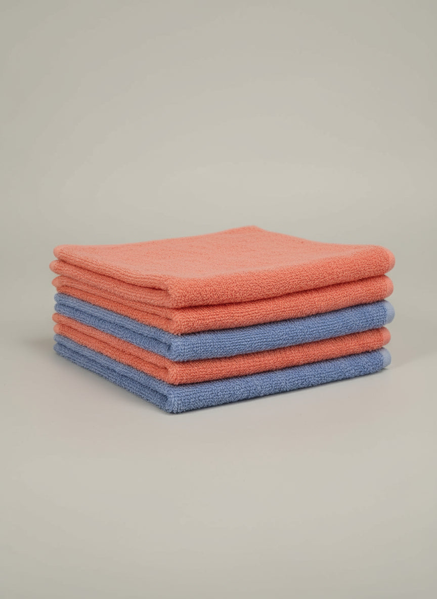 Blue towel on a cardboard box with a pink border on a tiled floor.