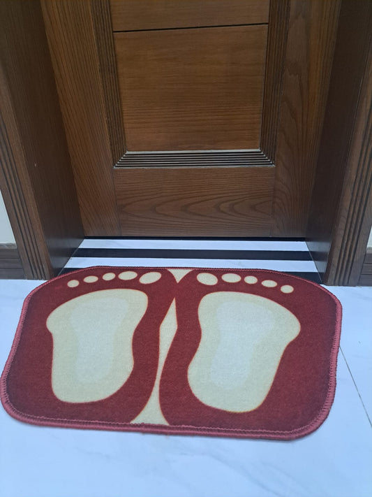 Red and beige doormat with footprints in front of a wooden door.