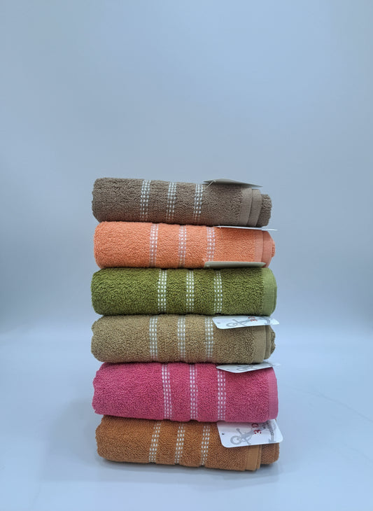 Stack of colorful towels with tags on a white surface