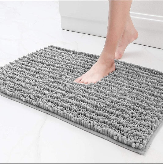 Gray bath mat on a white floor with a person stepping onto it.