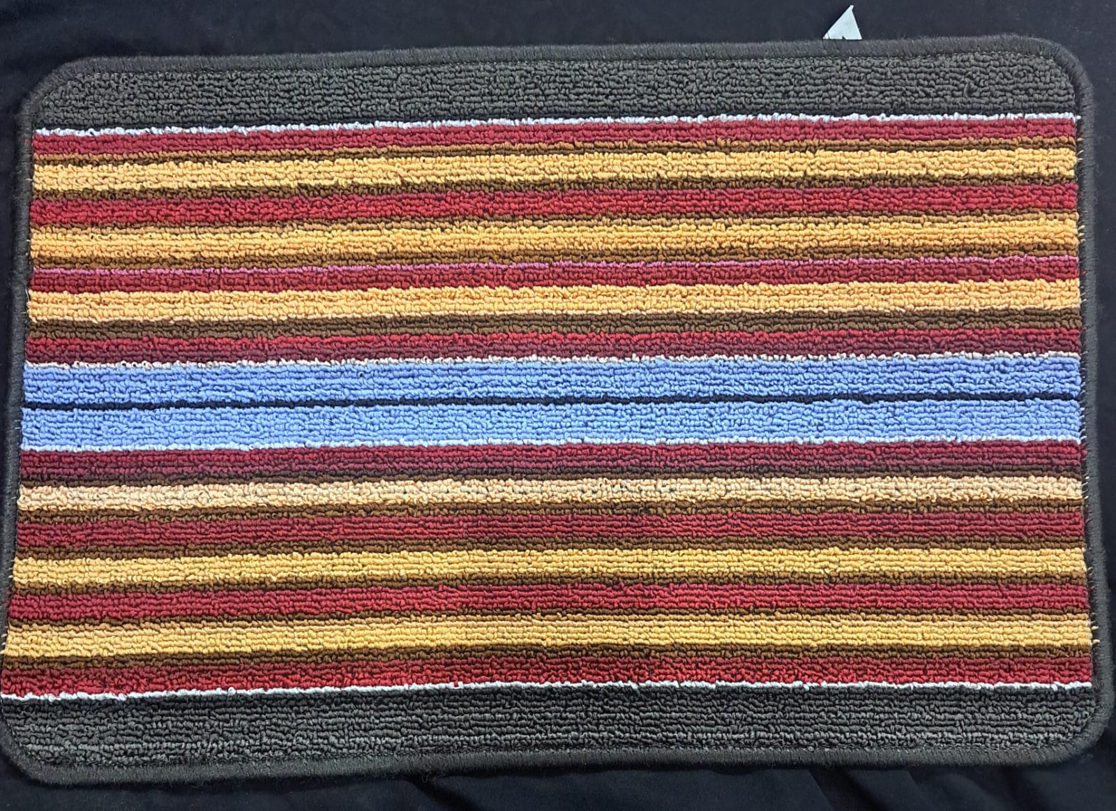 Striped bath mat with multicolor pattern on a dark background
