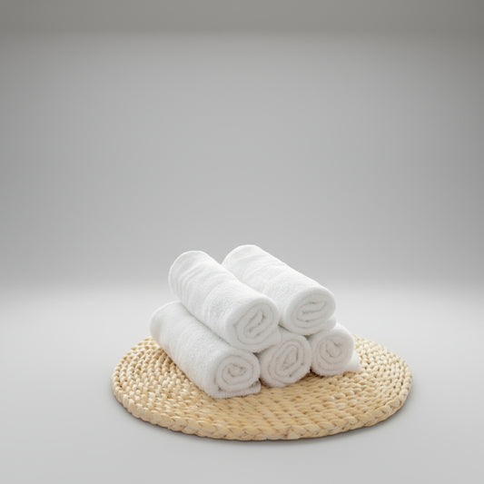 Stack of white towels on a woven mat with yellow tulips