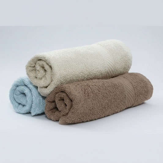 Three rolled-up towels in beige, brown, and white on a white background