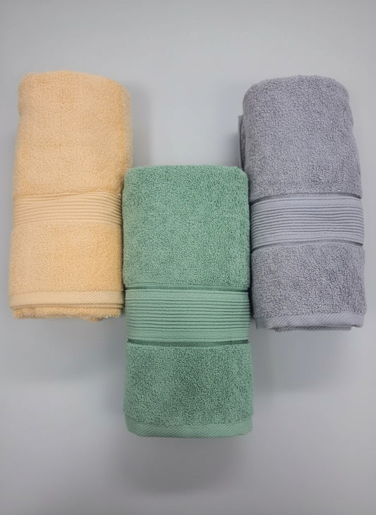 Three folded towels in beige, green, and gray on a black background