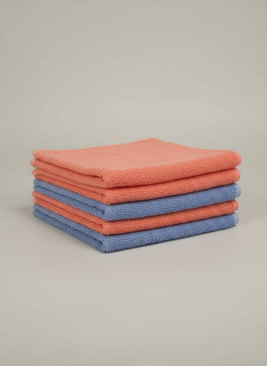 Blue towel on a cardboard box with a pink border on a tiled floor.