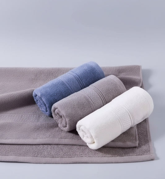 Three rolled-up towels in blue, gray, and white on a textured surface.